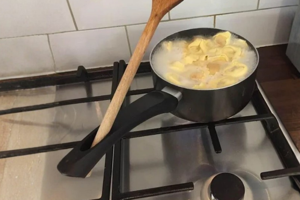 Wooden spoon resting through the hole of a saucepan handle