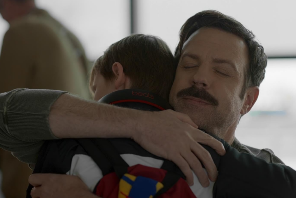 Jason Sudeikis as Ted Lasso hugging his son Henry at the airport