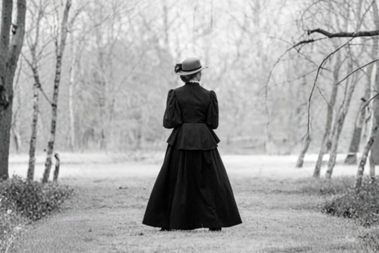 A woman in victorian attire gazes at a landscape.