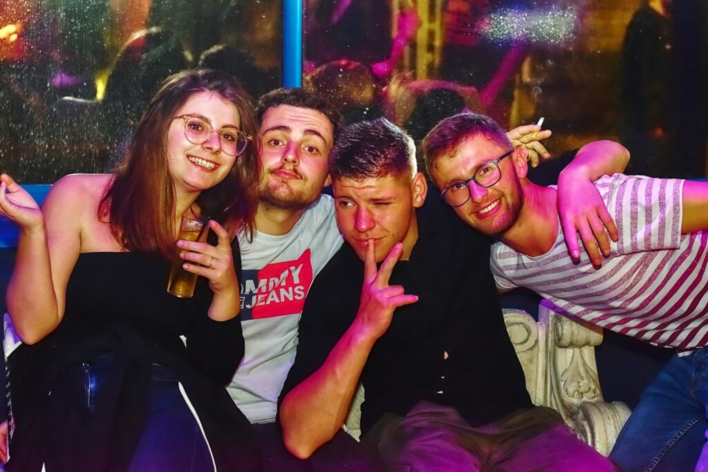 Four friends posing together in a dimly lit venue
