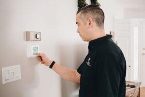 Person adjusting thermostat to a warmer summer setting