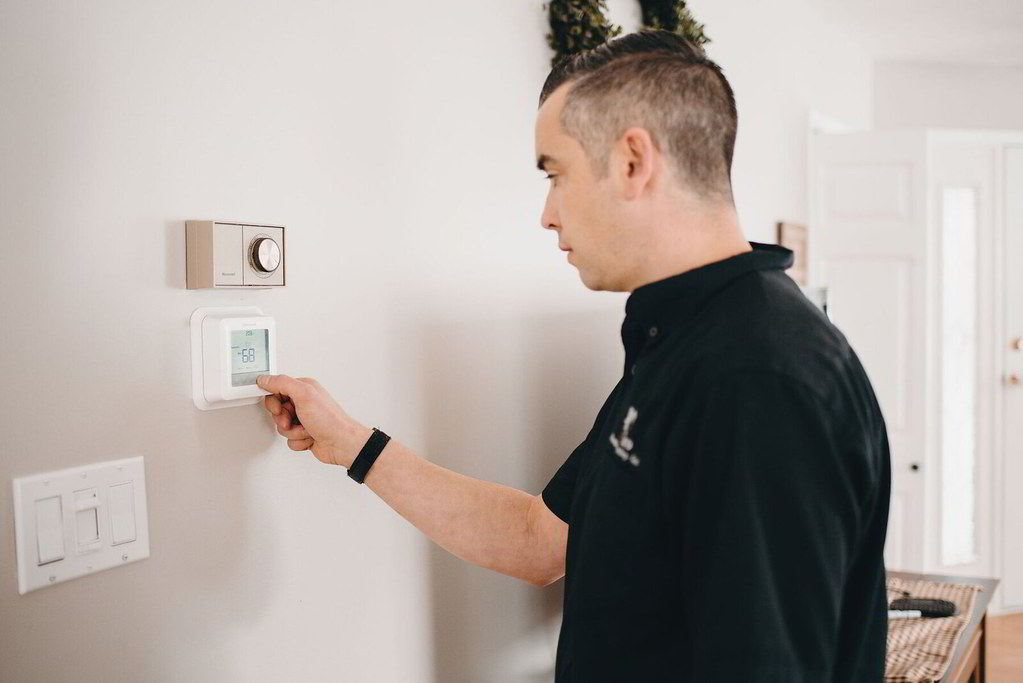 Person adjusting thermostat to a warmer summer setting