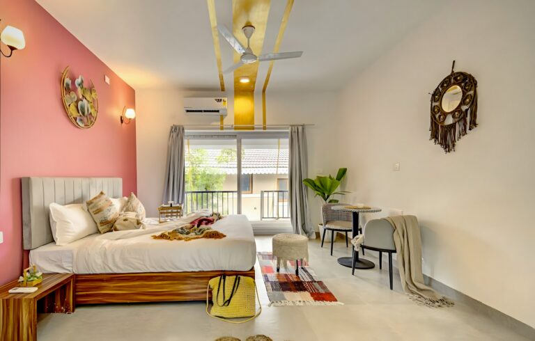 Cozy studio apartment with a bed, pink wall, and balcony.