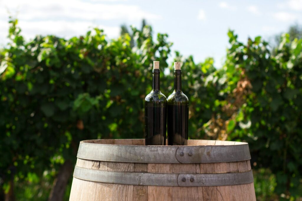 two black glass bottles on the top of the brown wooden barrel