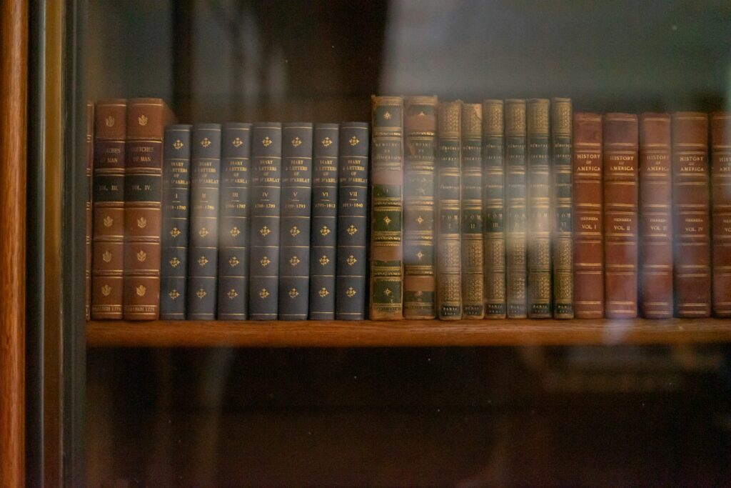 Row of antique books on a wooden shelf.