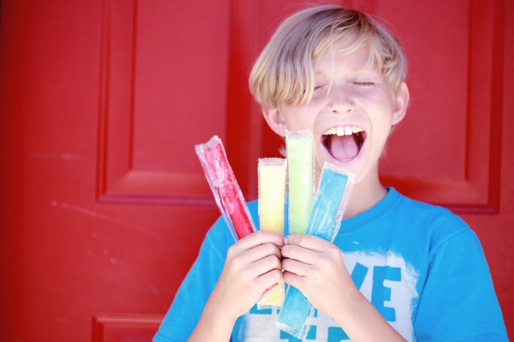 child holding four popsicle sticks for snacks