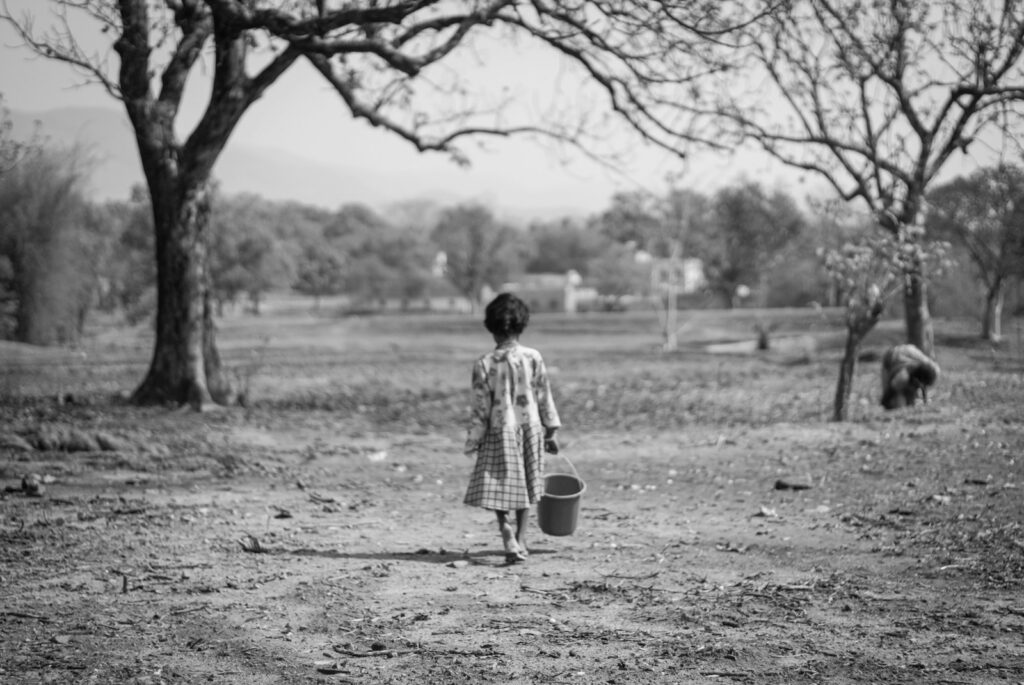a little girl that is standing in the dirt