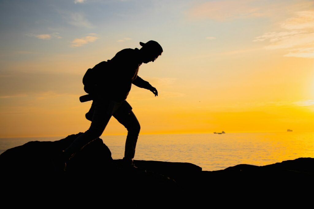 A person standing on a rock with the sun setting in the background