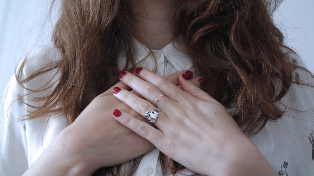 woman hands on heart wearing silver-colored ring