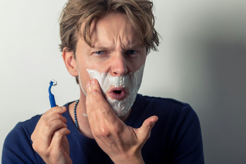 Man appears hurt or nicked while shaving with razor