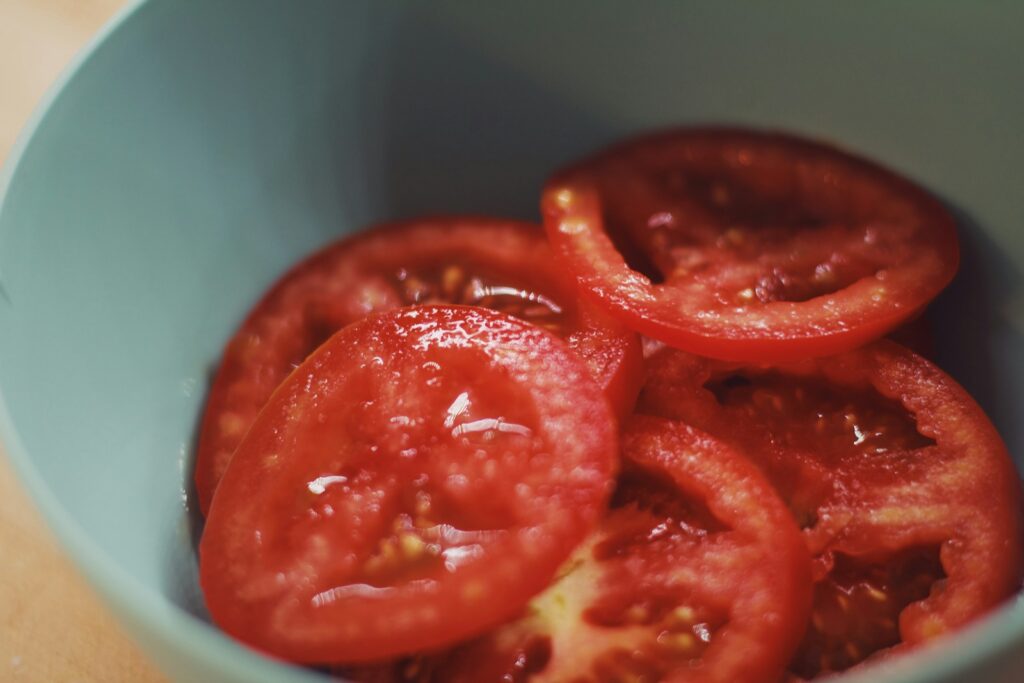 macro photography of sliced red tomatoes in green bowl