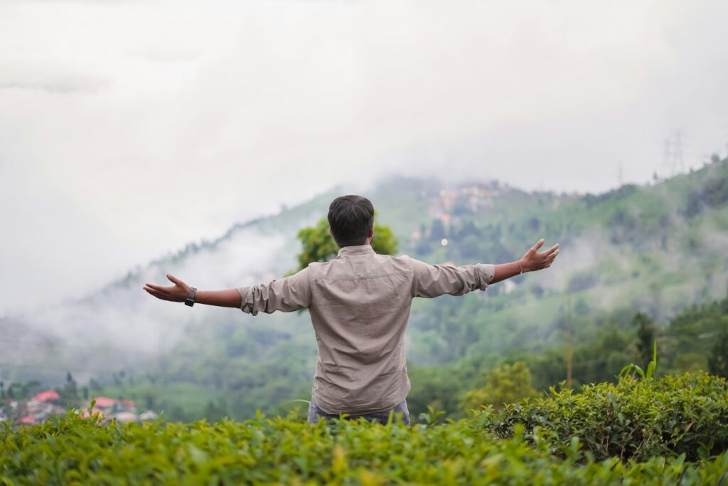 Man with arms outstretched on a misty mountain