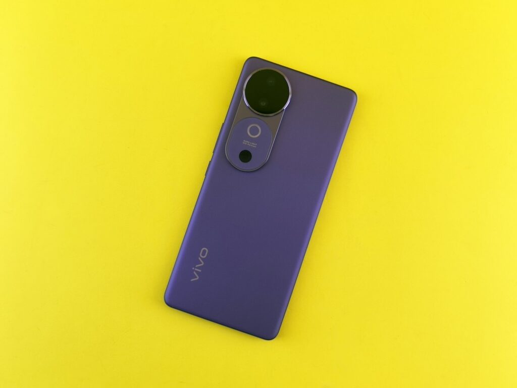 Purple smartphone with camera lens on a yellow background.