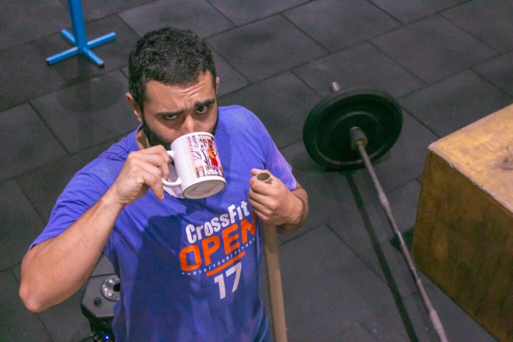 A man drinking from a cup while holding a stick