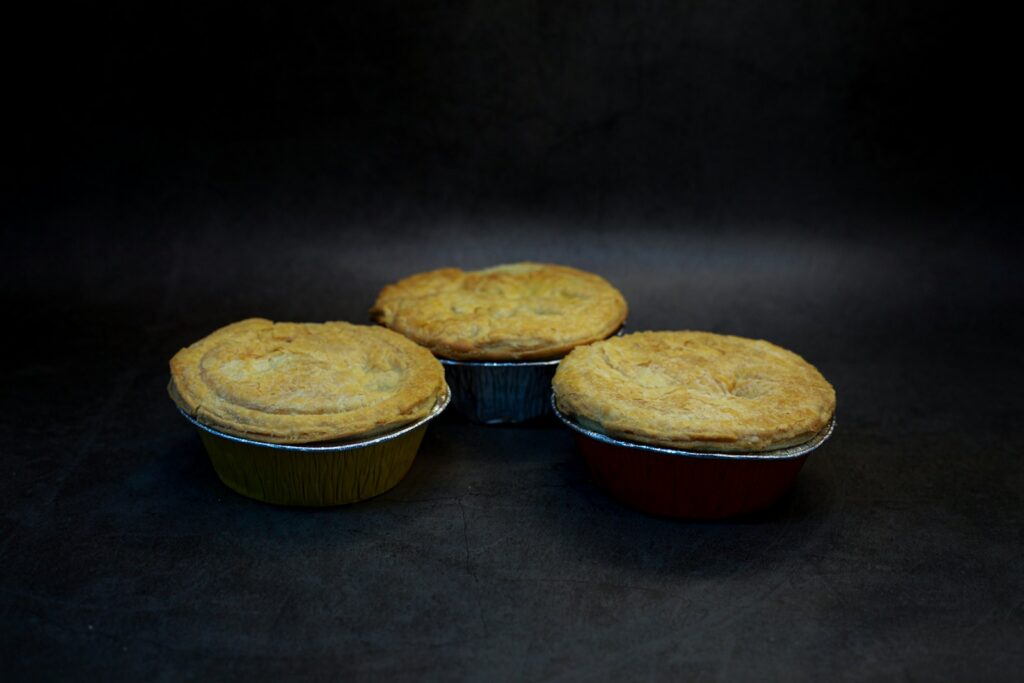 Three golden pies on a dark background