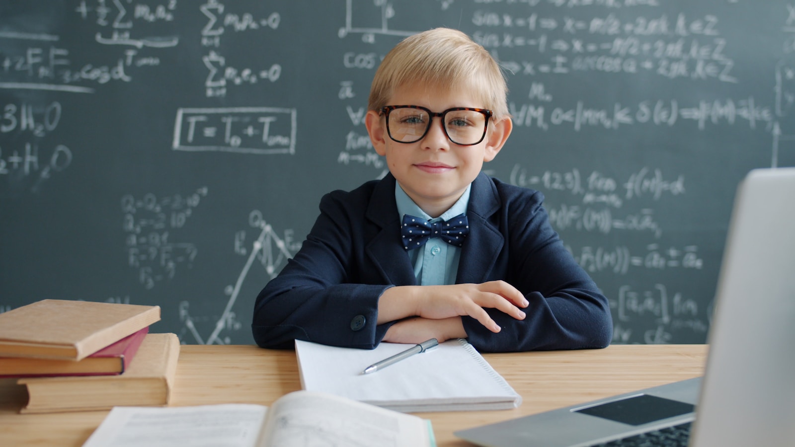 Young boy in glasses at desk with math equations