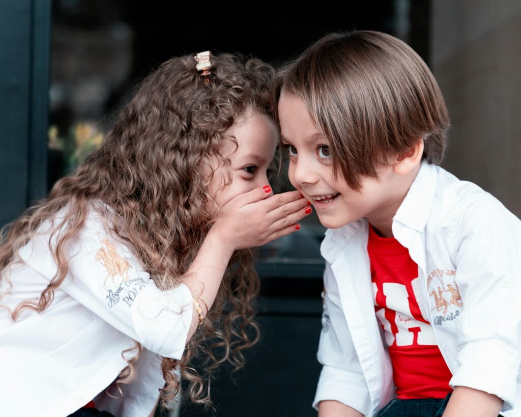 child in white long sleeve shirt whispering