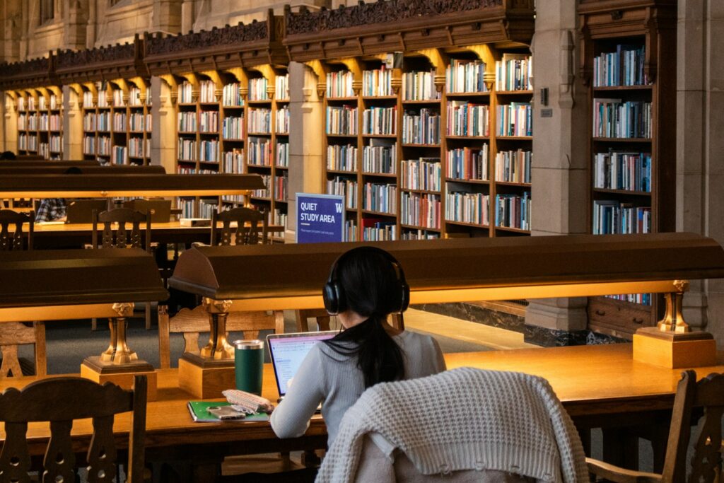 Student studies at a library with books.