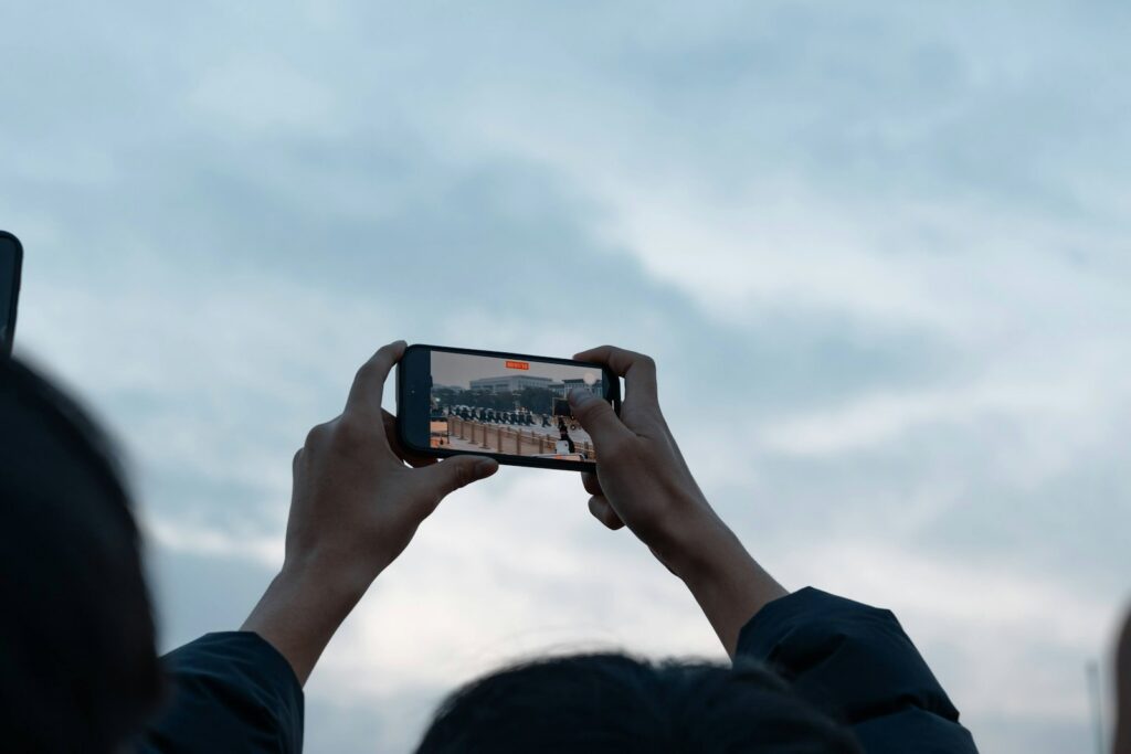 Hands holding smartphone recording a distant event