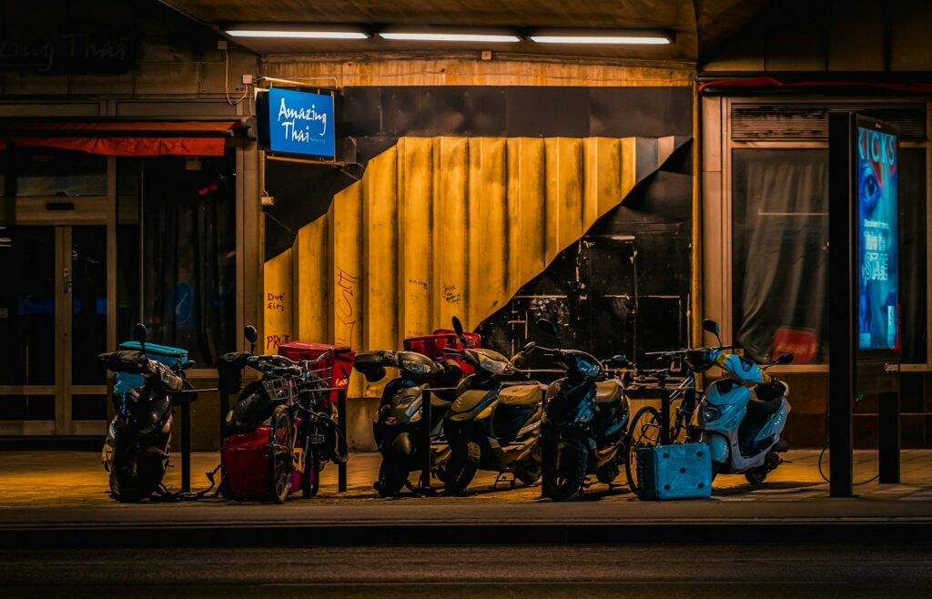 Delivery scooters parked outside a restaurant at night.
