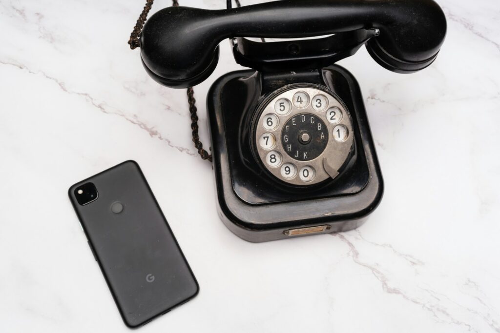 Black retro telephone beside smartphone