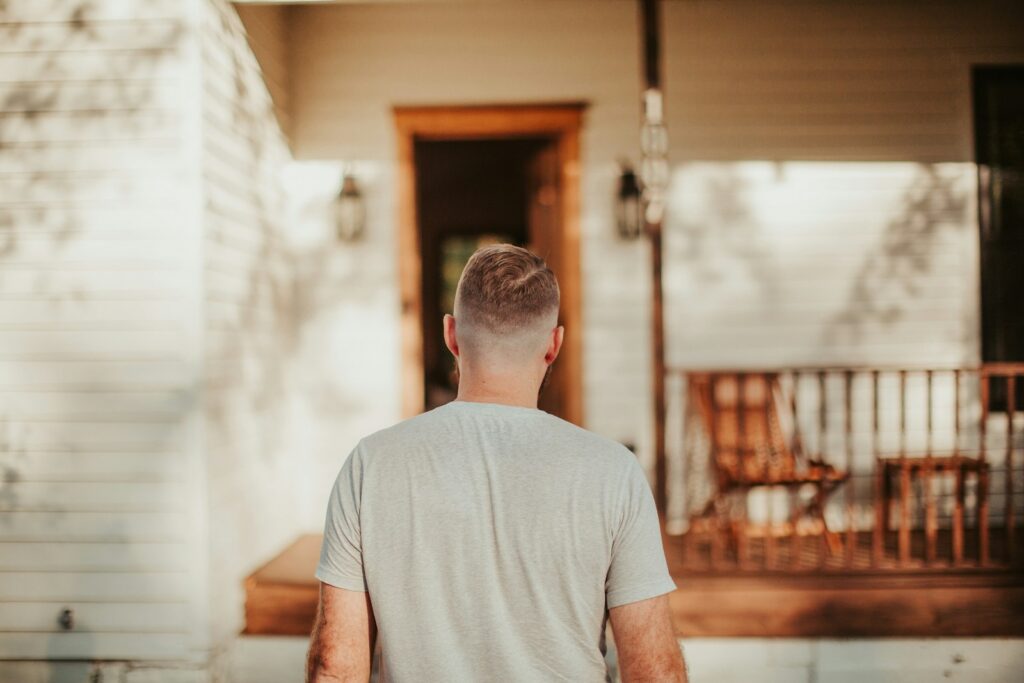 A man walking down a sidewalk towards a house