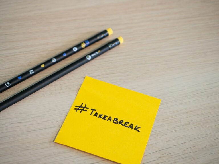 two pencils sitting on top of a yellow sticky note