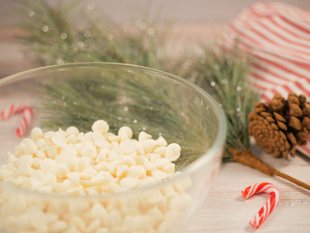 a bowl filled with marshmallows next to a pine cone