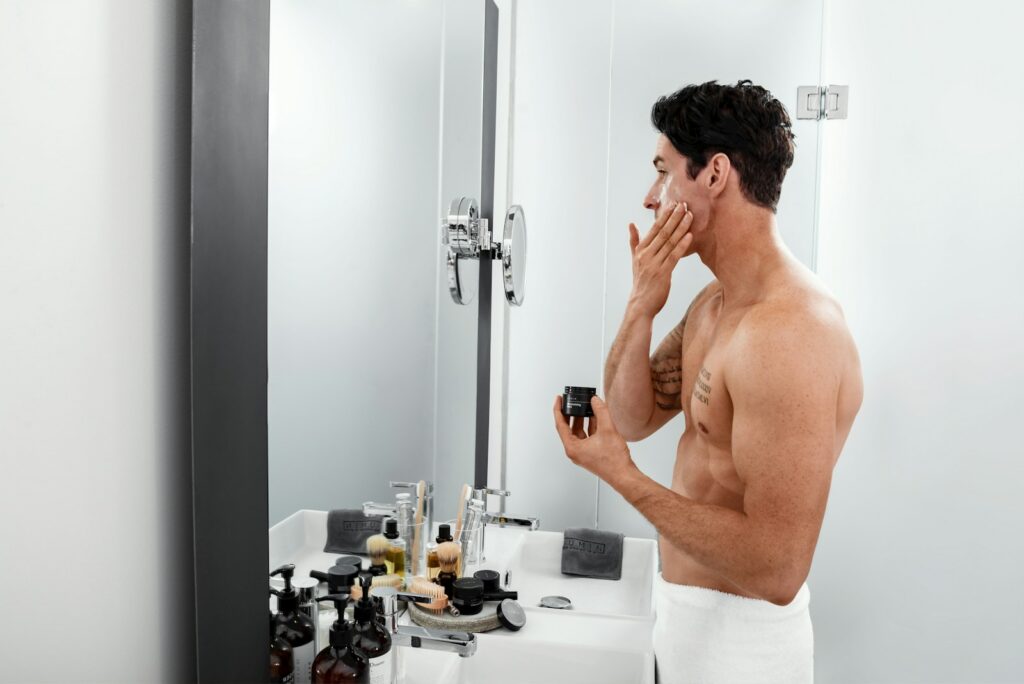 Topless man applying moisturizer after shaving