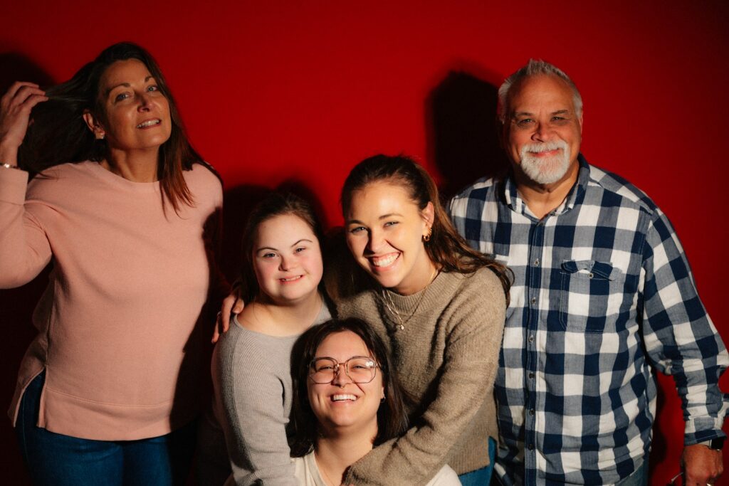 A family poses for a portrait against a red background.
