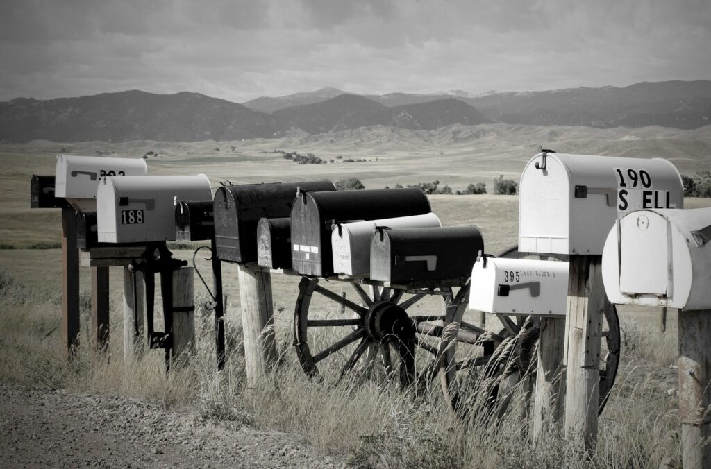 a group of white and black mailboxes in a field