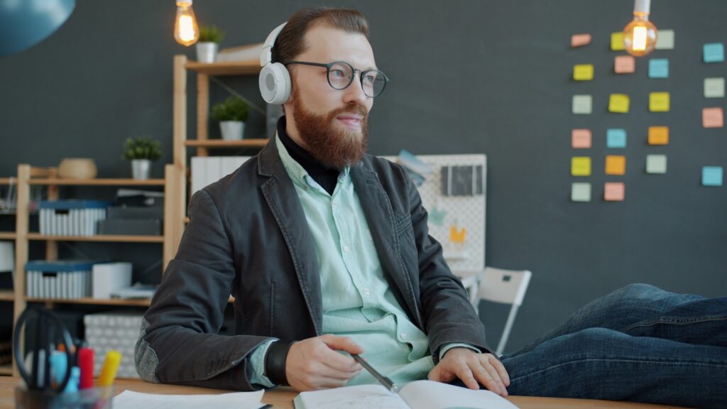 Man with headphones working at desk with notebook