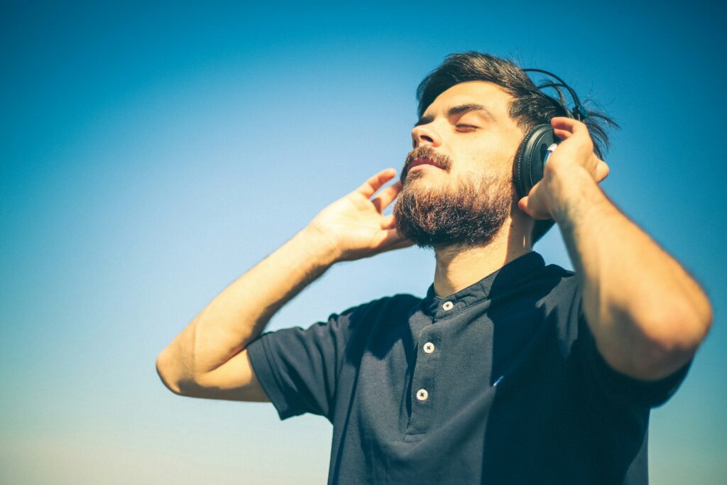 man in black polo shirt holding his head