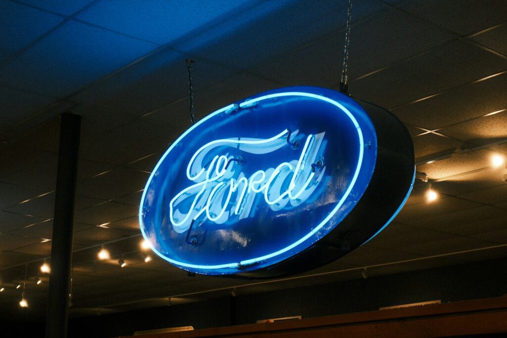 A blue neon ford logo sign hangs from the ceiling.
