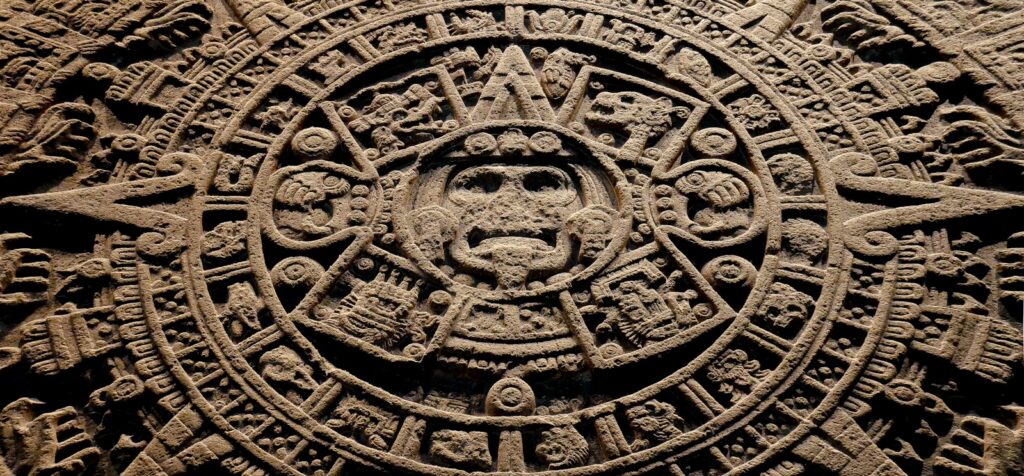 A stone carving of a face with many symbols on it