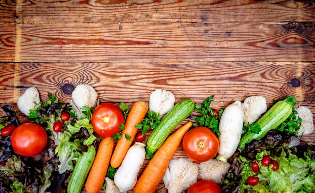 Fresh colorful vegetables arranged on a rustic wooden background.