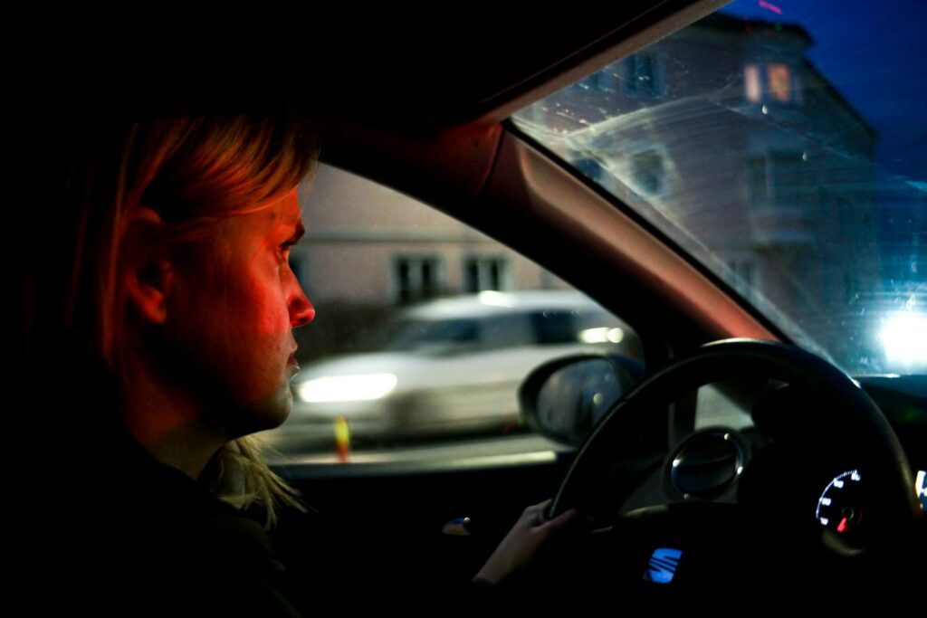 a woman driving a car in the dark