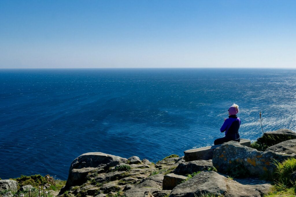 Woman meditating on cliff overlooking the ocean