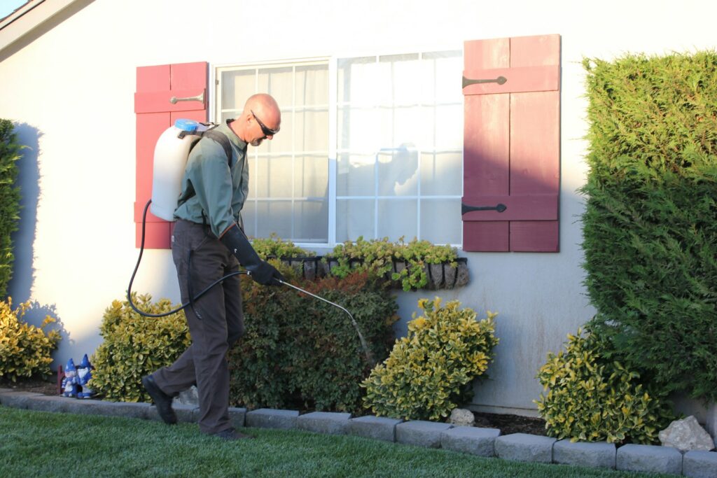 Pest-control technician with a vacuum in front of a house