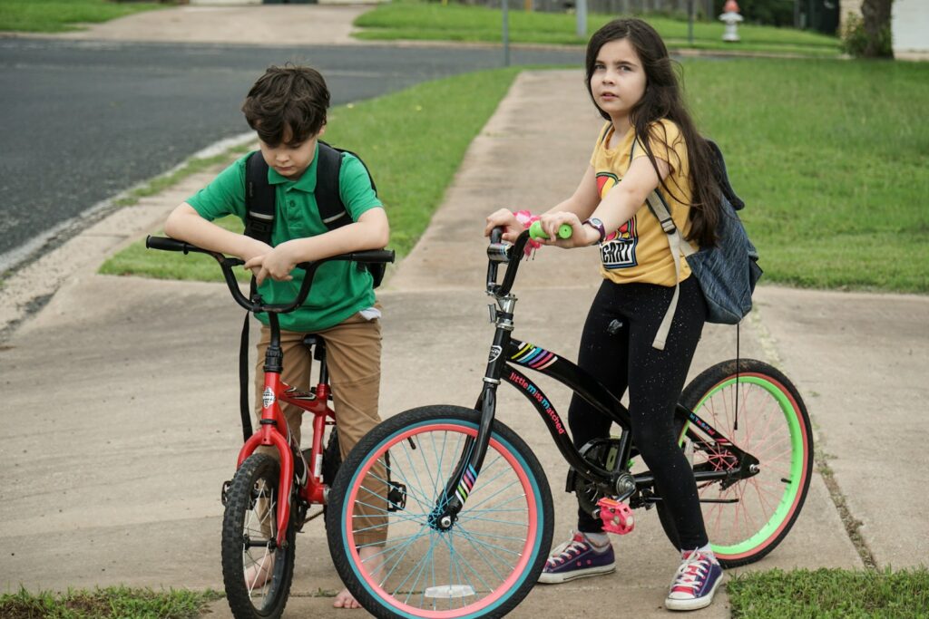 kid in green shirt riding red bicycle beside woman in green shirt during daytime