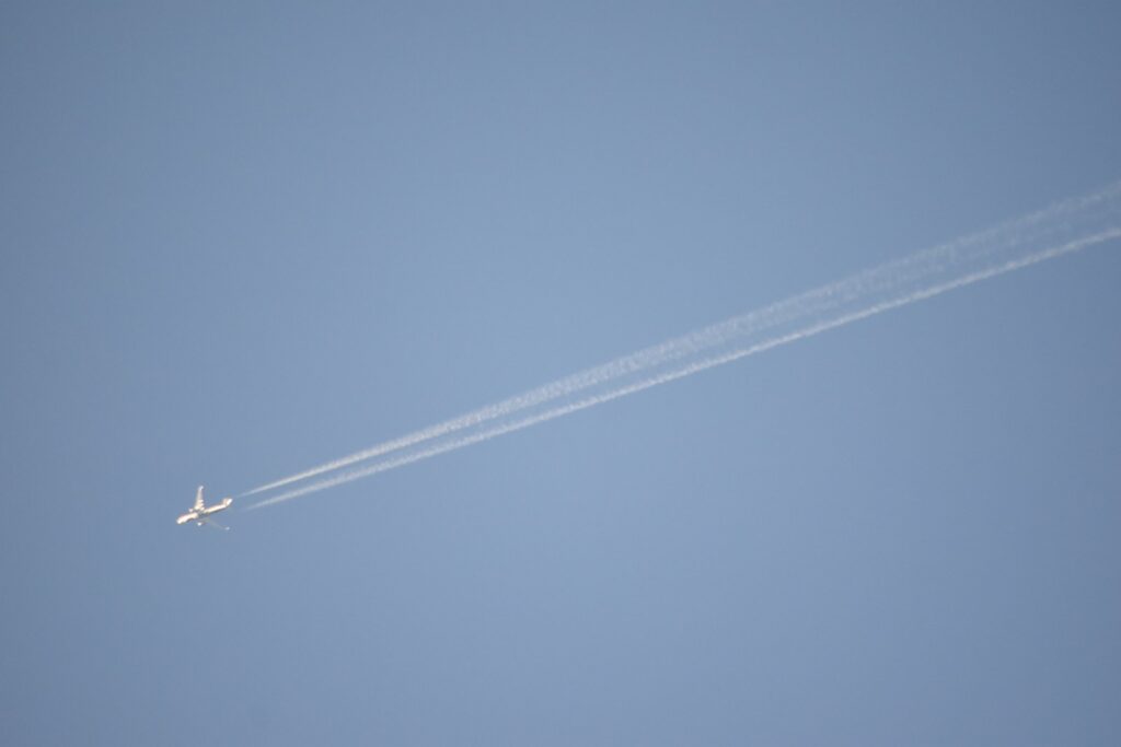 An airplane leaves a contrail across a clear blue sky.