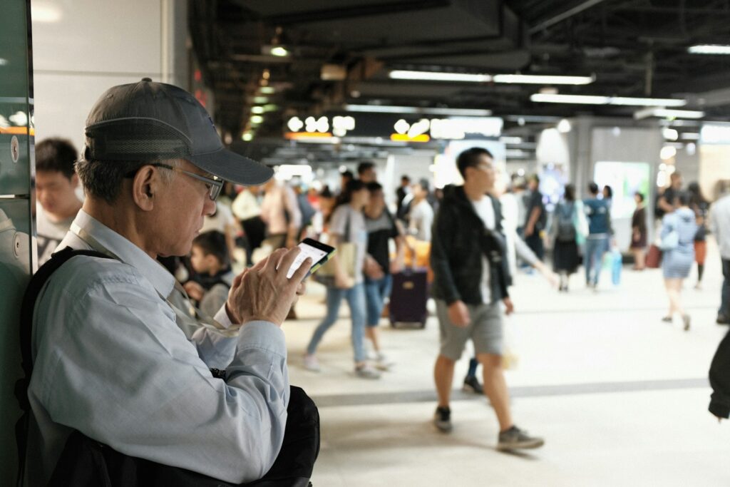 man in white dress shirt and black cap holding smartphone