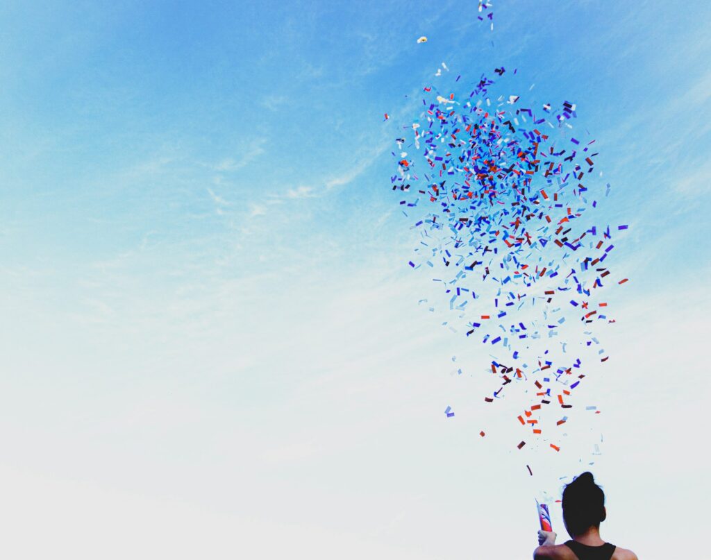 woman throwing confetti into blue sky