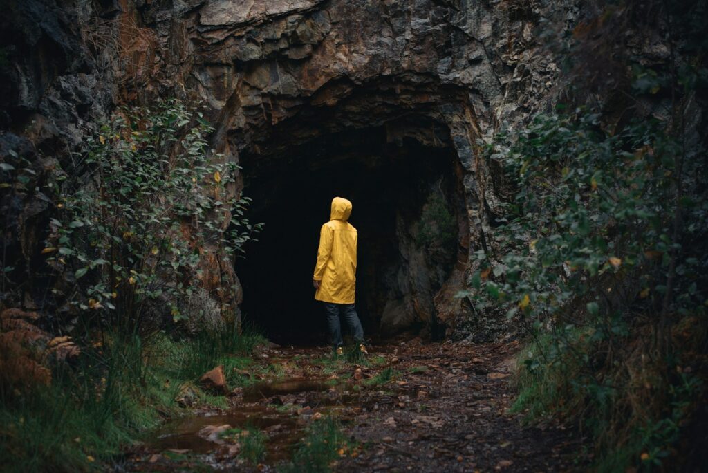 a person in a yellow jacket is standing in a cave, illustrating fear of unknown