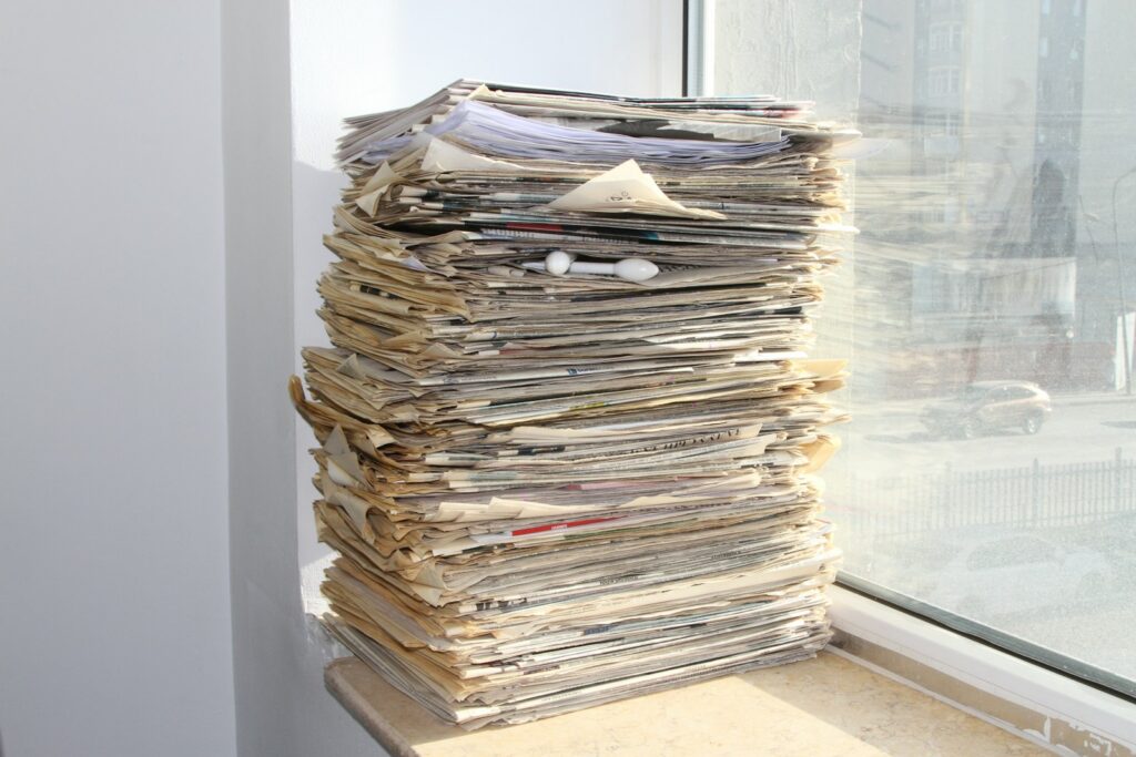 a stack of newspapers sitting on top of a window sill