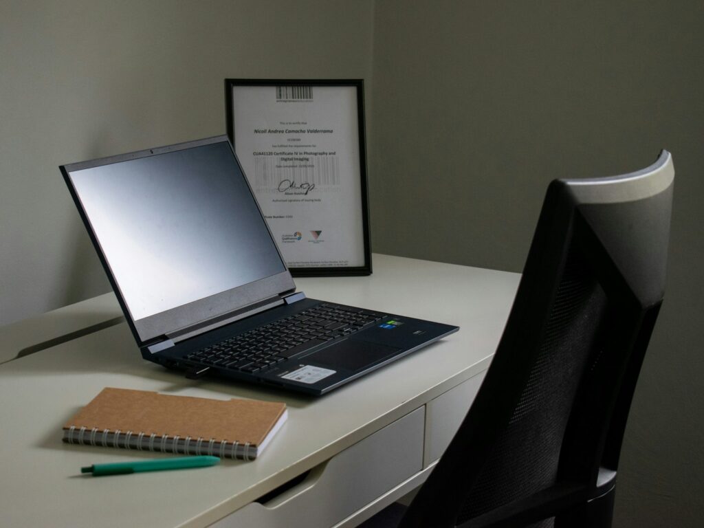 Laptop, notebook, and pen on a desk.
