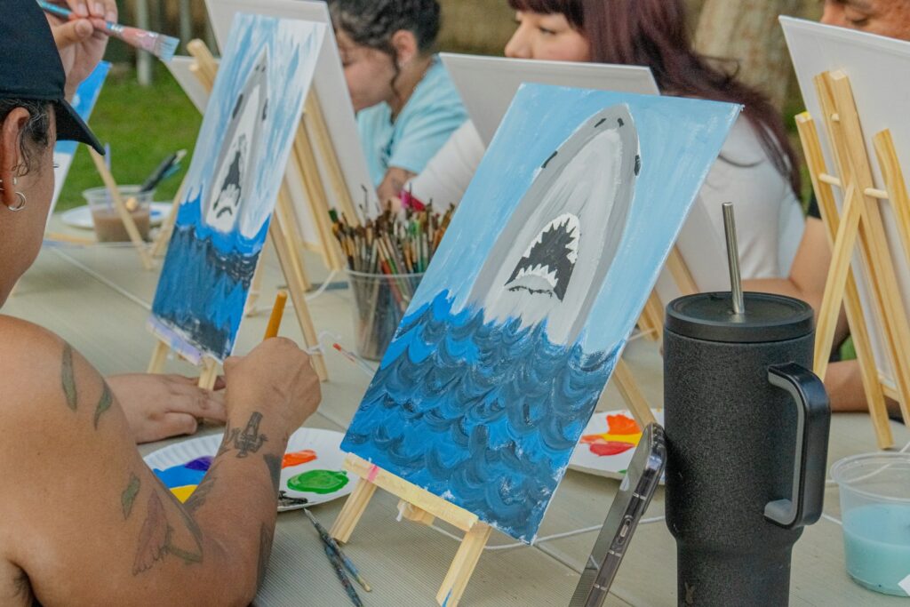 People are painting shark art on canvases.