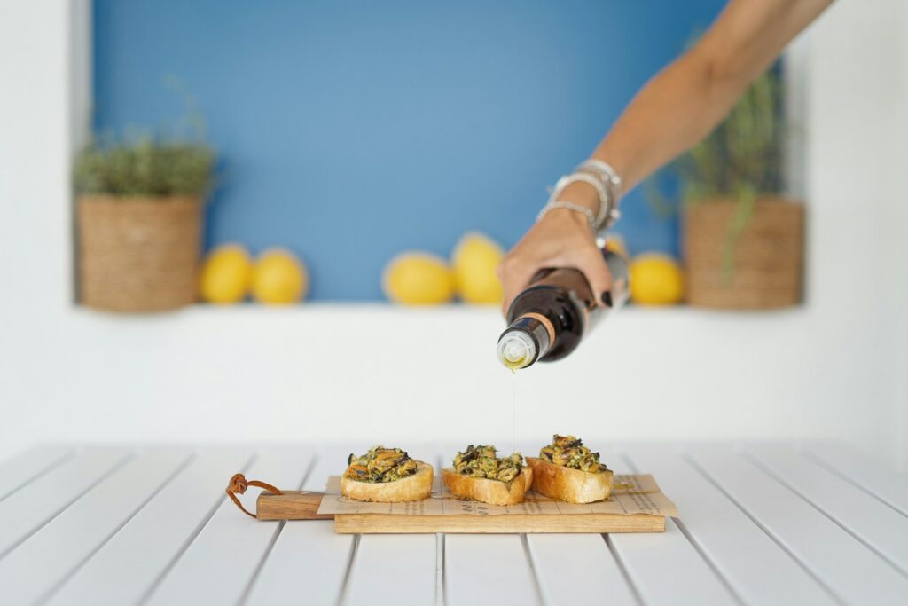 A person pouring a bottle of wine over a tray of food